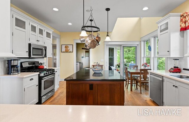 12857 Wilderness Trl, Grand Haven, MI 49417 - kitchen with appliances with stainless steel finishes, white cabinetry, backsplash, glass insert cabinets, and recessed lighting
