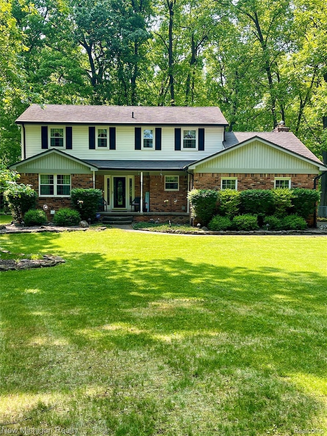 6567 Heaven Dr, Howell, MI 48855 - view of front of house with brick siding, a front lawn, covered porch, and view of wooded area