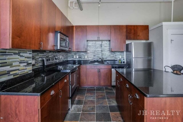 600 NW Broadway Ave Unit 318, Grand Rapids, MI 49504 - kitchen featuring appliances with stainless steel finishes, a sink, tasteful backsplash, dark stone finish flooring, and dark stone countertops