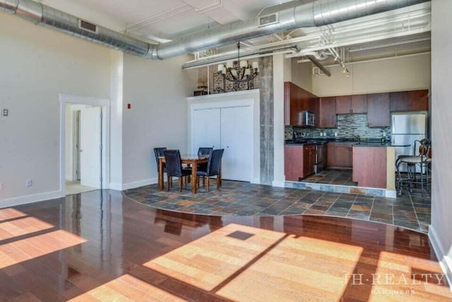 600 NW Broadway Ave Unit 318, Grand Rapids, MI 49504 - kitchen with a high ceiling, appliances with stainless steel finishes, dark countertops, dark wood-style flooring, and tasteful backsplash