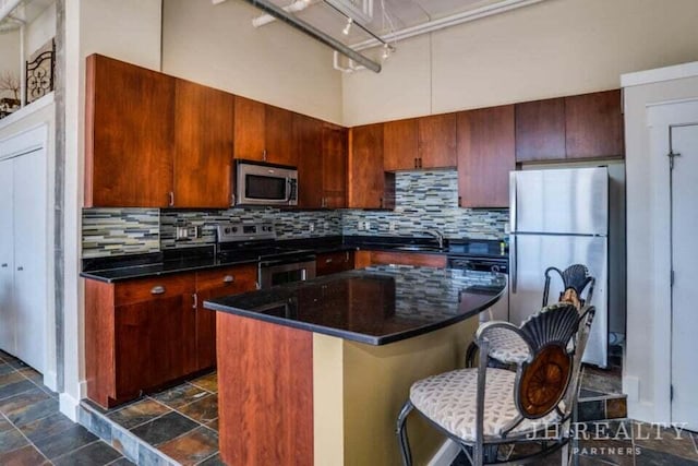 600 NW Broadway Ave Unit 318, Grand Rapids, MI 49504 - kitchen with stainless steel appliances, tasteful backsplash, a center island, and dark stone finish floors