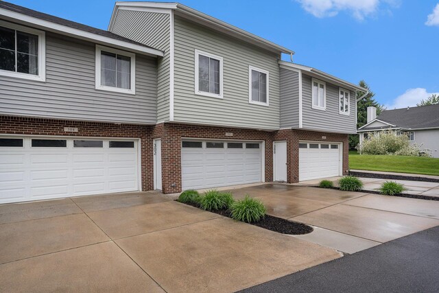 302 NE Xing, Holland, MI 49423 - view of front facade with concrete driveway, an attached garage, and brick siding