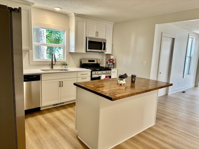1200 Pine St, Muskegon, MI 49442 - kitchen with appliances with stainless steel finishes, wooden counters, a sink, light wood-style floors, and a textured ceiling