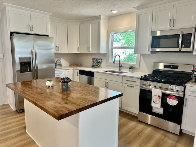1200 Pine St, Muskegon, MI 49442 - kitchen featuring appliances with stainless steel finishes, a sink, wood counters, light wood finished floors, and white cabinets