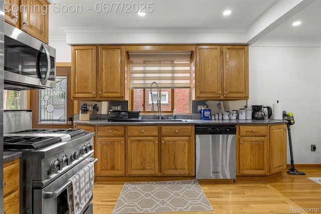 8786 N Evangeline St, Dearborn Heights, MI 48127 - kitchen featuring stainless steel appliances, dark countertops, brown cabinetry, light wood finished floors, and a sink