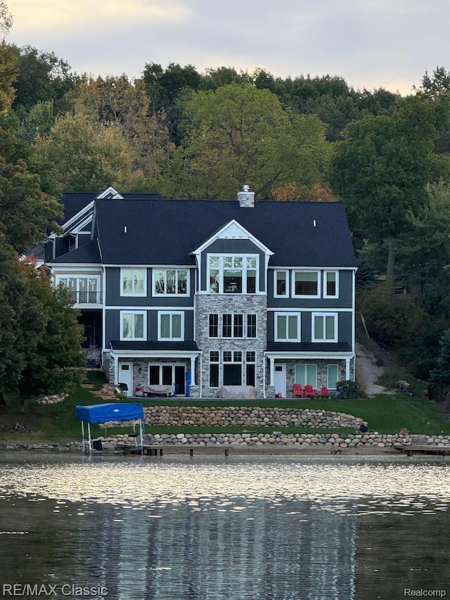 4087 Araby Ct, Highland, MI 48356 - back of house with a water view, stone siding, and a view of trees