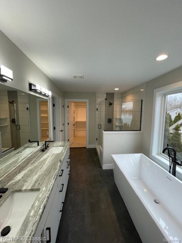 4087 Araby Ct, Highland, MI 48356 - full bath featuring a stall shower, double vanity, a walk in closet, a soaking tub, and recessed lighting