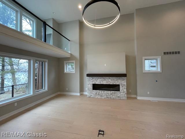 4087 Araby Ct, Highland, MI 48356 - unfurnished living room featuring a towering ceiling, plenty of natural light, baseboards, wood finished floors, and recessed lighting