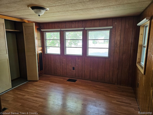 2270 Gulfstream St, Brighton, MI 48114 - unfurnished bedroom with wood finished floors, a closet, wood walls, and baseboards