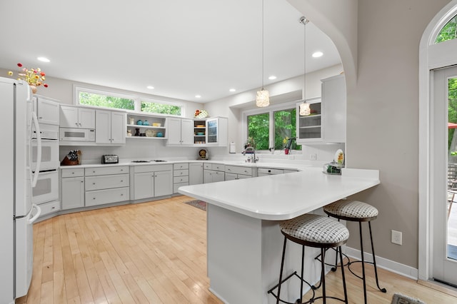 7843 Shepherds Glen Ct, Kalamazoo, MI 49009 - kitchen with a peninsula, white appliances, a breakfast bar, plenty of natural light, and recessed lighting