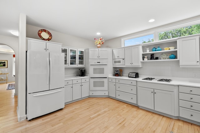 7843 Shepherds Glen Ct, Kalamazoo, MI 49009 - kitchen featuring white appliances, decorative backsplash, light wood-style floors, light countertops, and arched walkways