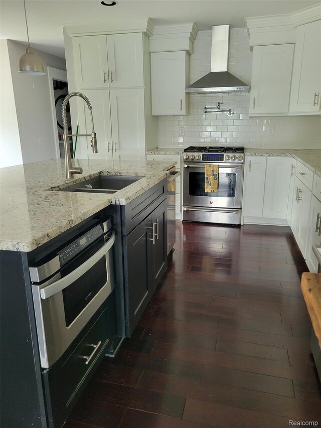 9635 Norman Rd, Clarkston, MI 48348 - kitchen featuring appliances with stainless steel finishes, wall chimney exhaust hood, a sink, and dark wood-style floors