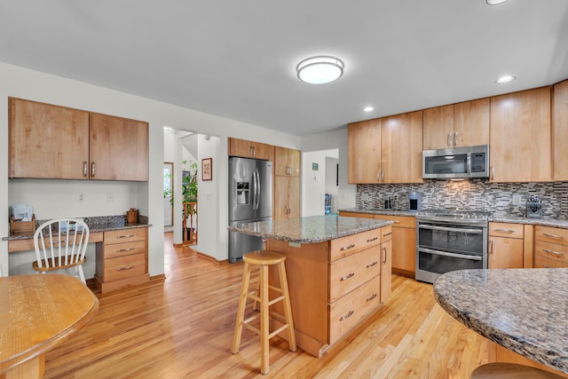 6676 Ralaric Dr, Dexter, MI 48130 - kitchen with appliances with stainless steel finishes, a breakfast bar area, light wood finished floors, tasteful backsplash, and recessed lighting