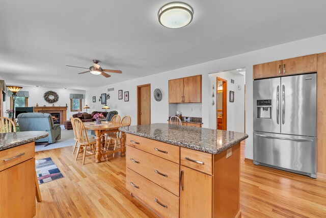 6676 Ralaric Dr, Dexter, MI 48130 - kitchen featuring stainless steel refrigerator with ice dispenser, light wood finished floors, a fireplace, ceiling fan, and a center island