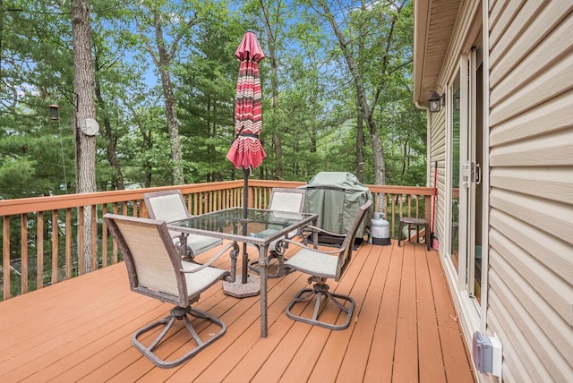 8833 W Velt Ave, Baldwin, MI 49304 - deck featuring outdoor dining area, view of wooded area, and grilling area