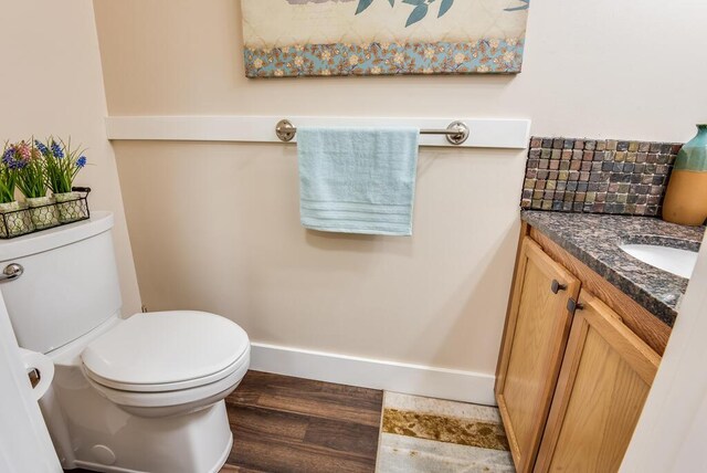 8833 W Velt Ave, Baldwin, MI 49304 - half bath with vanity, toilet, backsplash, wood finished floors, and baseboards