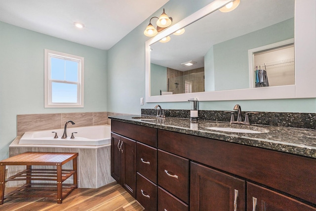 1162 Cooks Corner Ct SE, Byron Center, MI 49315 - bathroom with double vanity, a bath, wood finished floors, tiled shower, and a spacious closet