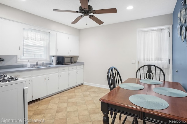 300 Cornell St, Howell, MI 48843 - kitchen with stainless steel microwave, a sink, ceiling fan, white range with gas stovetop, and white cabinets