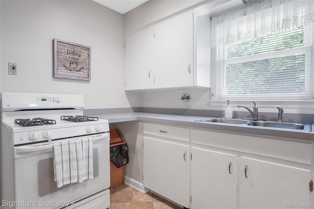 300 Cornell St, Howell, MI 48843 - kitchen with white gas range oven, a sink, white cabinetry, light countertops, and light tile patterned floors