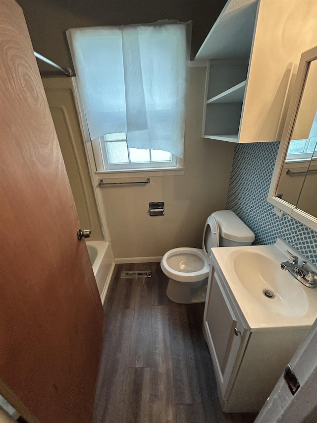 1015 Alvord Ave, Flint, MI 48507 - bathroom featuring toilet, wood finished floors, vanity, decorative backsplash, and baseboards