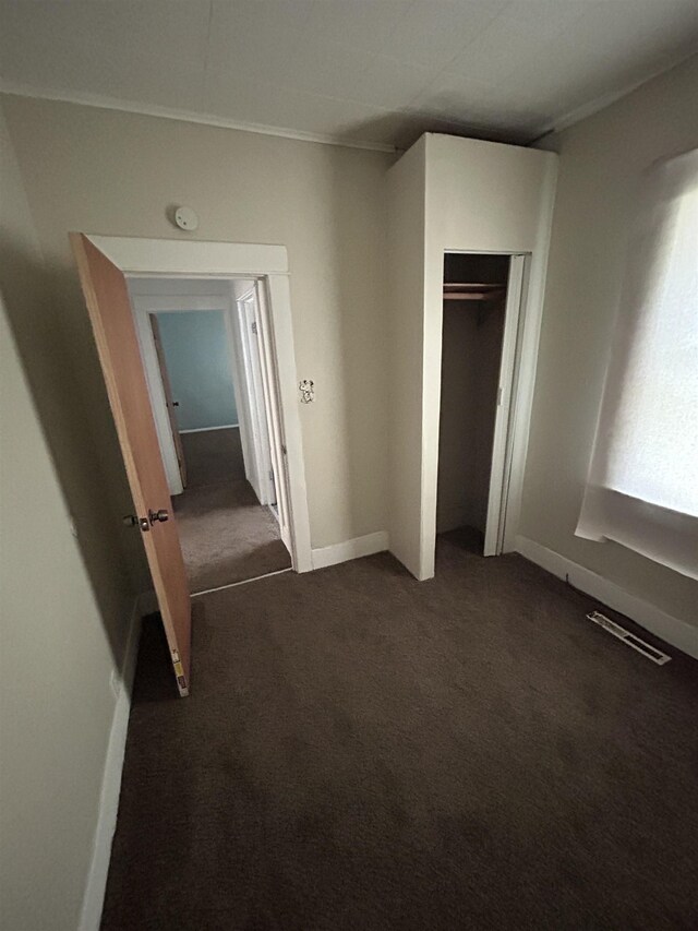 1015 Alvord Ave, Flint, MI 48507 - unfurnished bedroom with dark carpet, a closet, baseboards, and crown molding