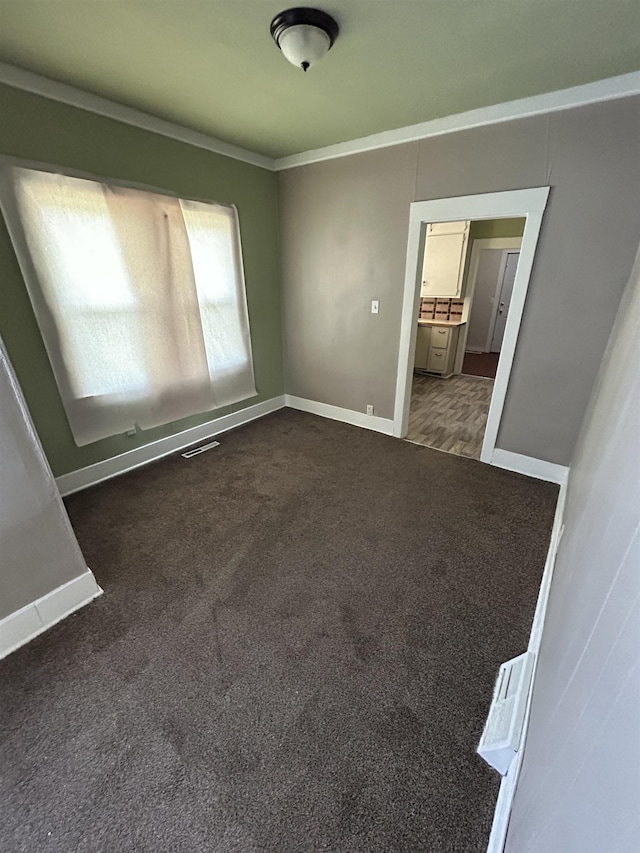 1015 Alvord Ave, Flint, MI 48507 - spare room with ornamental molding, baseboards, and dark colored carpet