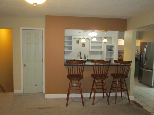 6005 Saint Joseph Ave, Stevensville, MI 49127 - kitchen with stainless steel fridge, open shelves, a kitchen bar, a peninsula, and dark countertops