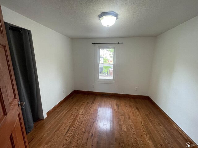 6301 E Albain Rd, Monroe, MI 48161 - empty room featuring wood finished floors, a textured ceiling, and baseboards
