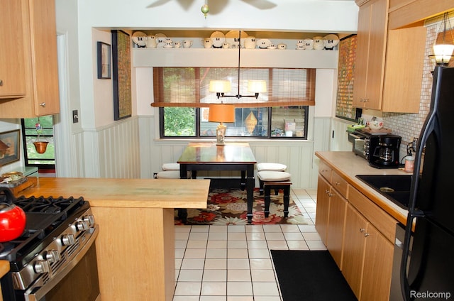 1410 Culver Ave, Dearborn, MI 48124 - kitchen with a wainscoted wall, freestanding refrigerator, light tile patterned floors, stainless steel gas range oven, and a chandelier