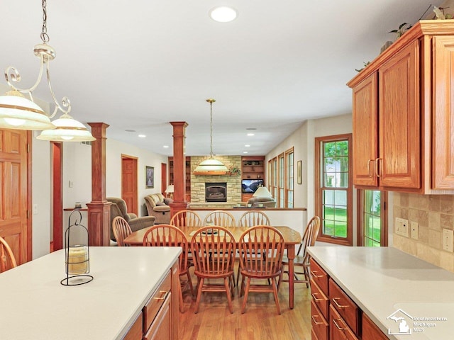 9241 Legacy Ct, Temperance, MI 48182 - kitchen featuring decorative columns, light wood-type flooring, open floor plan, light countertops, and a fireplace