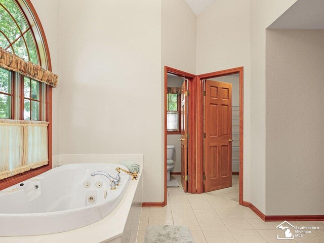 9241 Legacy Ct, Temperance, MI 48182 - full bath featuring a towering ceiling, toilet, a jetted tub, tile patterned floors, and baseboards