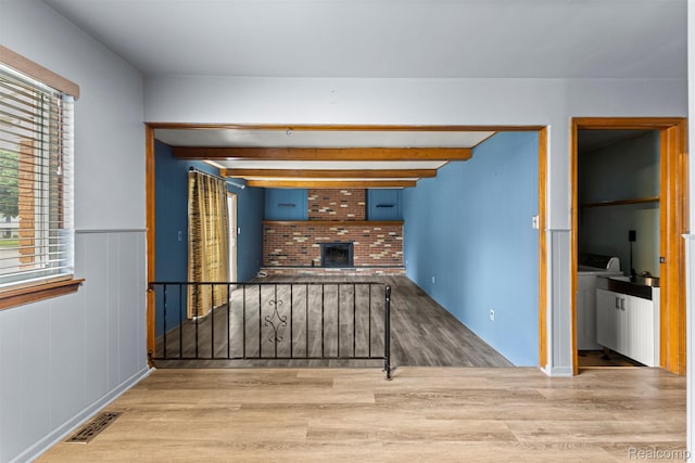 18607 Colonial Ct, Allen Park, MI 48101 - unfurnished living room featuring wood finished floors, beam ceiling, a brick fireplace, and wainscoting