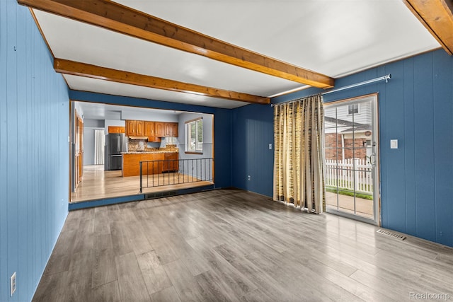 18607 Colonial Ct, Allen Park, MI 48101 - unfurnished living room featuring beam ceiling, light wood-style floors, and wooden walls