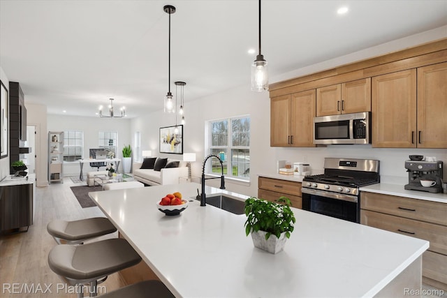 1685 Pinecroft Ln, Howell, MI 48855 - kitchen with stainless steel appliances, a sink, light wood-type flooring, a chandelier, and light countertops