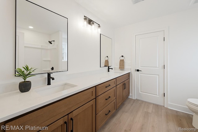 1685 Pinecroft Ln, Howell, MI 48855 - full bathroom with toilet, double vanity, wood finished floors, a shower, and baseboards