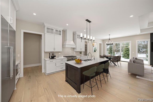 4174 Prescott Park Cir W, Bloomfield, MI 48323 - kitchen with custom exhaust hood, high end appliances, a chandelier, light wood-style flooring, and light countertops
