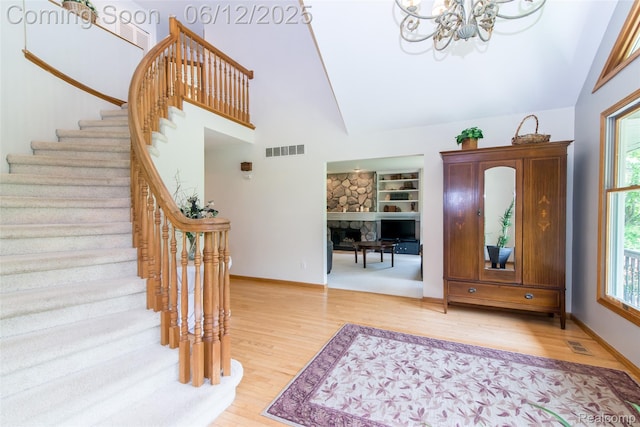 10399 Allen Rd, Clarkston, MI 48348 - entrance foyer featuring a chandelier, light wood-style floors, stairs, a fireplace, and high vaulted ceiling