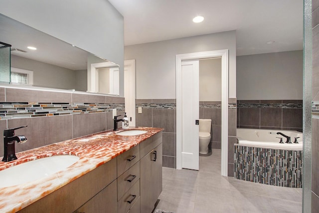 371 Waukazoo Dr, Holland, MI 49424 - full bathroom with tile walls, double vanity, a bath, toilet, and tile patterned flooring