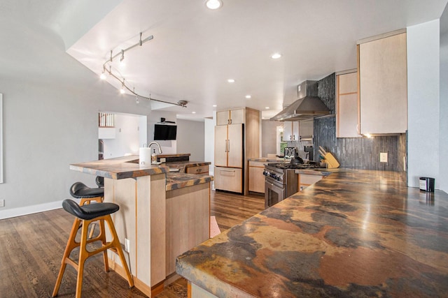 371 Waukazoo Dr, Holland, MI 49424 - kitchen with high quality appliances, wall chimney exhaust hood, a kitchen bar, a kitchen island with sink, and wood finished floors