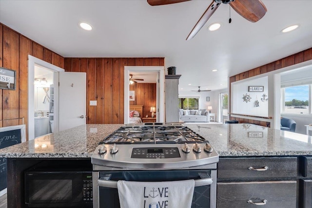 4805 Pinellas Dr, Hale, MI 48739 - kitchen with a ceiling fan, gas stove, black microwave, wood walls, and open floor plan