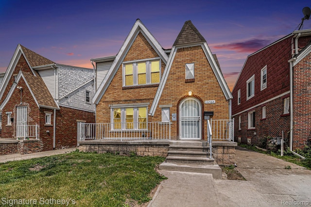 16762 Woodingham Dr, Detroit, MI 48221 - tudor-style house featuring brick siding, a shingled roof, and a porch