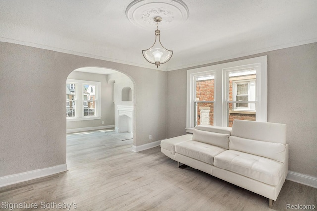 16762 Woodingham Dr, Detroit, MI 48221 - living area with arched walkways, baseboards, wood finished floors, a textured wall, and crown molding