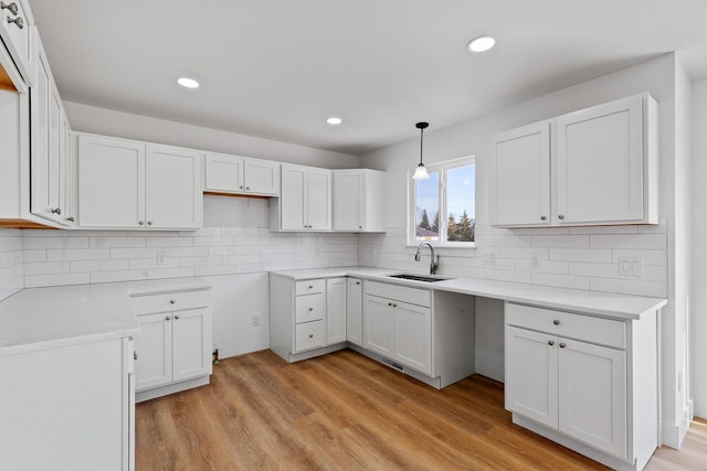 2023 Green Acres Dr, Adrian, MI 49221 - kitchen with a sink, light wood-style flooring, tasteful backsplash, white cabinetry, and recessed lighting