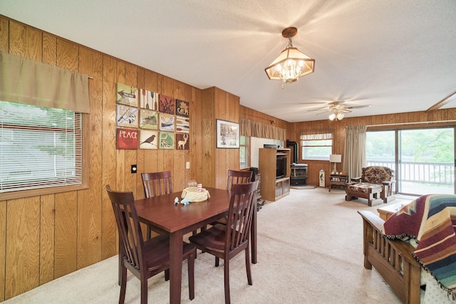 6387 N Larson Rd, Fountain, MI 49410 - dining room with a wood stove, light carpet, a chandelier, wooden walls, and ceiling fan
