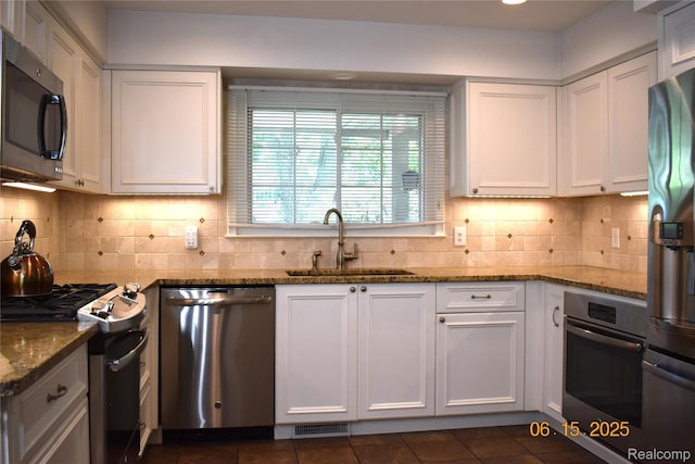 6560 Perham Dr, West Bloomfield, MI 48322 - kitchen featuring appliances with stainless steel finishes, white cabinetry, dark tile patterned flooring, and tasteful backsplash