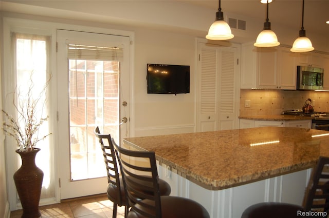 6560 Perham Dr, West Bloomfield, MI 48322 - kitchen with appliances with stainless steel finishes, backsplash, light stone counters, a kitchen bar, and pendant lighting