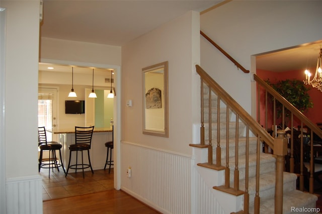 6560 Perham Dr, West Bloomfield, MI 48322 - staircase with a wainscoted wall, wood finished floors, a chandelier, and radiator heating unit