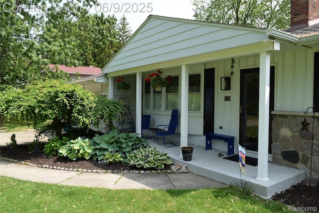 6009 Lancaster Dr, Flint, MI 48532 - view of exterior entry featuring a porch, board and batten siding, and a chimney
