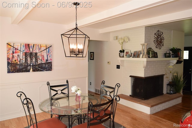 6009 Lancaster Dr, Flint, MI 48532 - dining space featuring wood finished floors, beam ceiling, a chandelier, and a brick fireplace