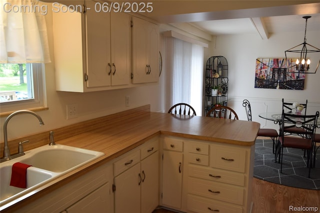 6009 Lancaster Dr, Flint, MI 48532 - kitchen featuring beamed ceiling, a sink, light countertops, and white cabinetry